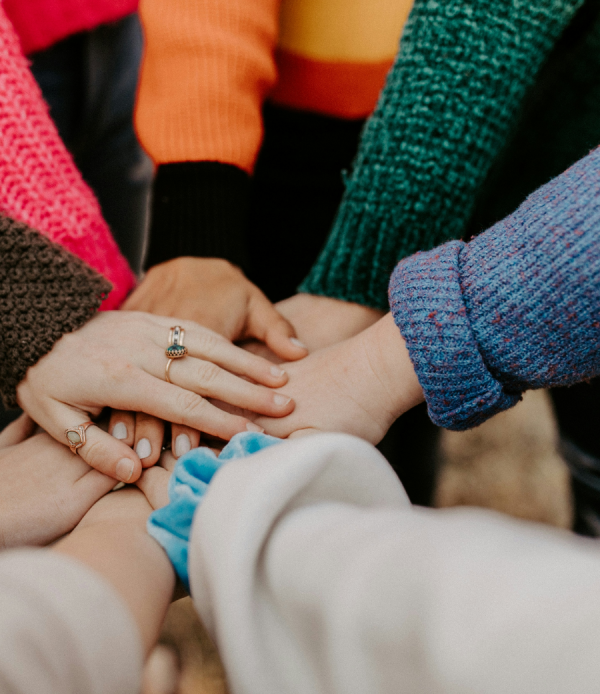 women standing in a circle placing hands on top of each other